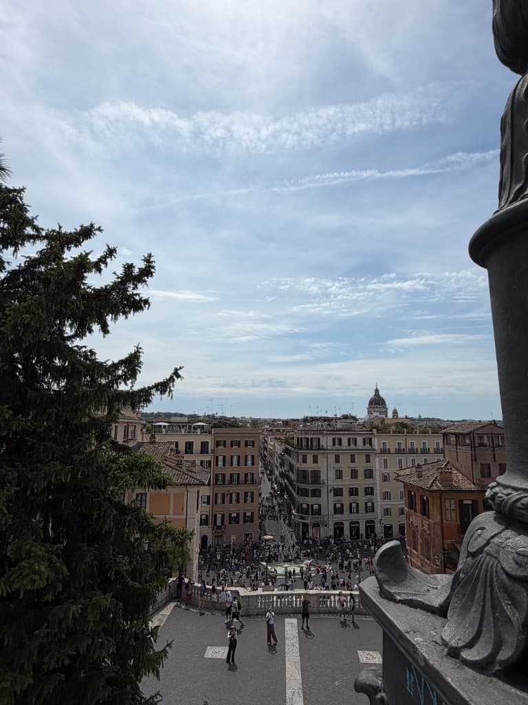 A high view from the Spanish Steps in Rome looking toward Via dei Condotti and the city skyline.