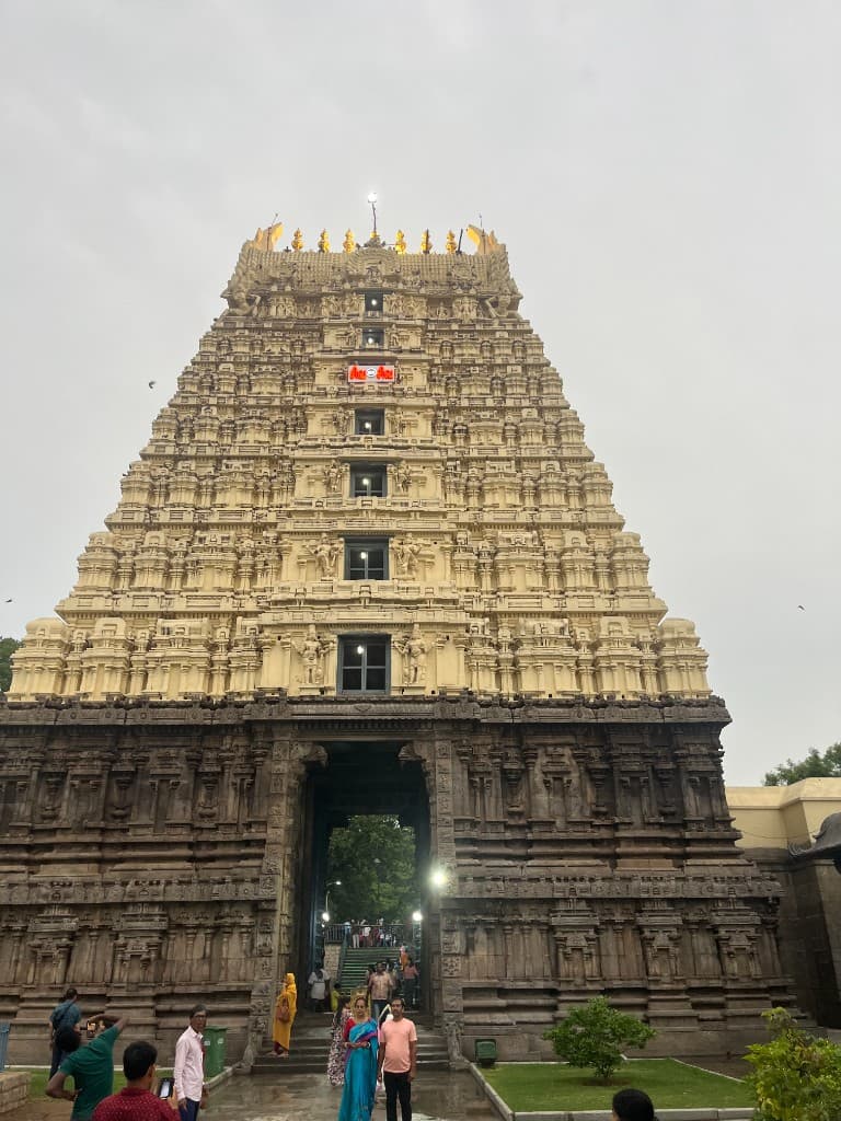 A multi-tiered Hindu temple entrance tower with intricate carvings and people gathered at the gateway.
